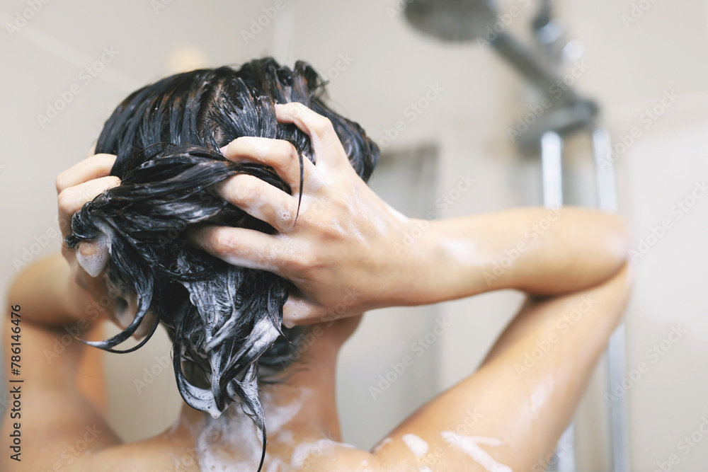 Naklejka premium Woman is washing her hair with shampoo.