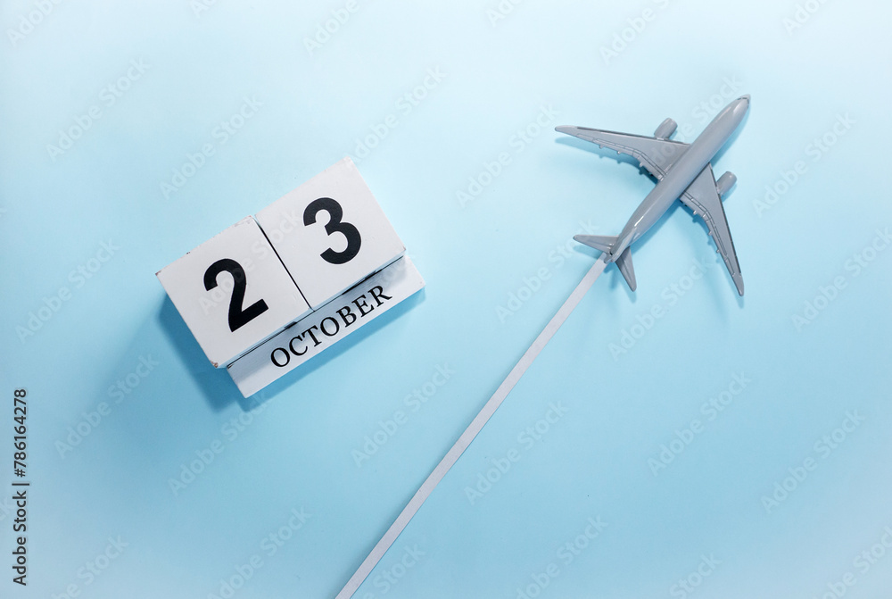 October calendar with number 23. Top view of a calendar with a flying passenger plane. Scheduler. Travel concept. Copy space. October calendar with number 23. Top view of a calendar with a flying passenger plane. Scheduler. Travel concept. Copy space.