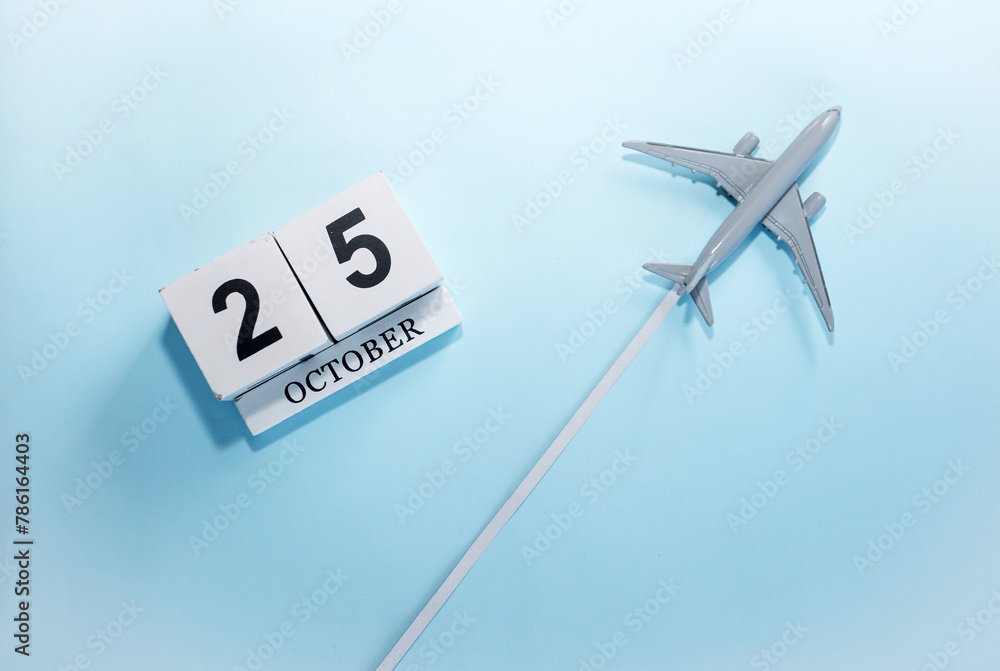 October calendar with number 25. Top view of a calendar with a flying passenger plane. Scheduler. Travel concept. Copy space. October calendar with number 25. Top view of a calendar with a flying passenger plane. Scheduler. Travel concept. Copy space.