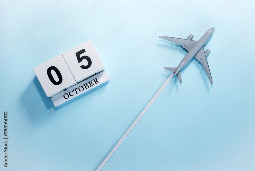 October calendar with number 5. Top view of a calendar with a flying passenger plane. Scheduler. Travel concept. Copy space. October calendar with number 5. Top view of a calendar with a flying passenger plane. Scheduler. Travel concept. Copy space.