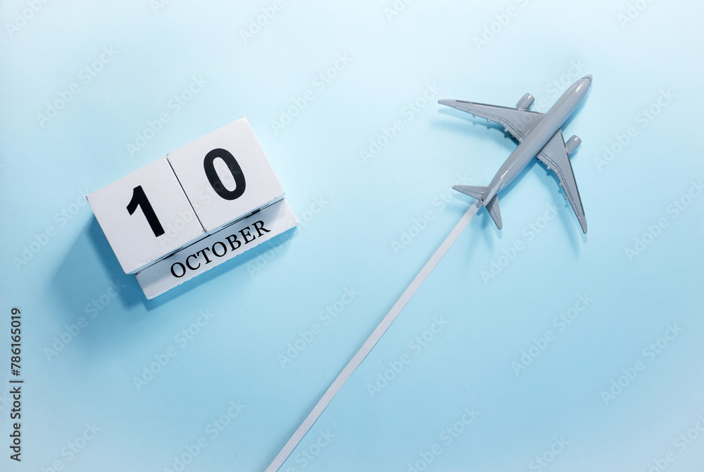 October calendar with number 10. Top view of a calendar with a flying passenger plane. Scheduler. Travel concept. Copy space. October calendar with number 10. Top view of a calendar with a flying passenger plane. Scheduler. Travel concept. Copy space.