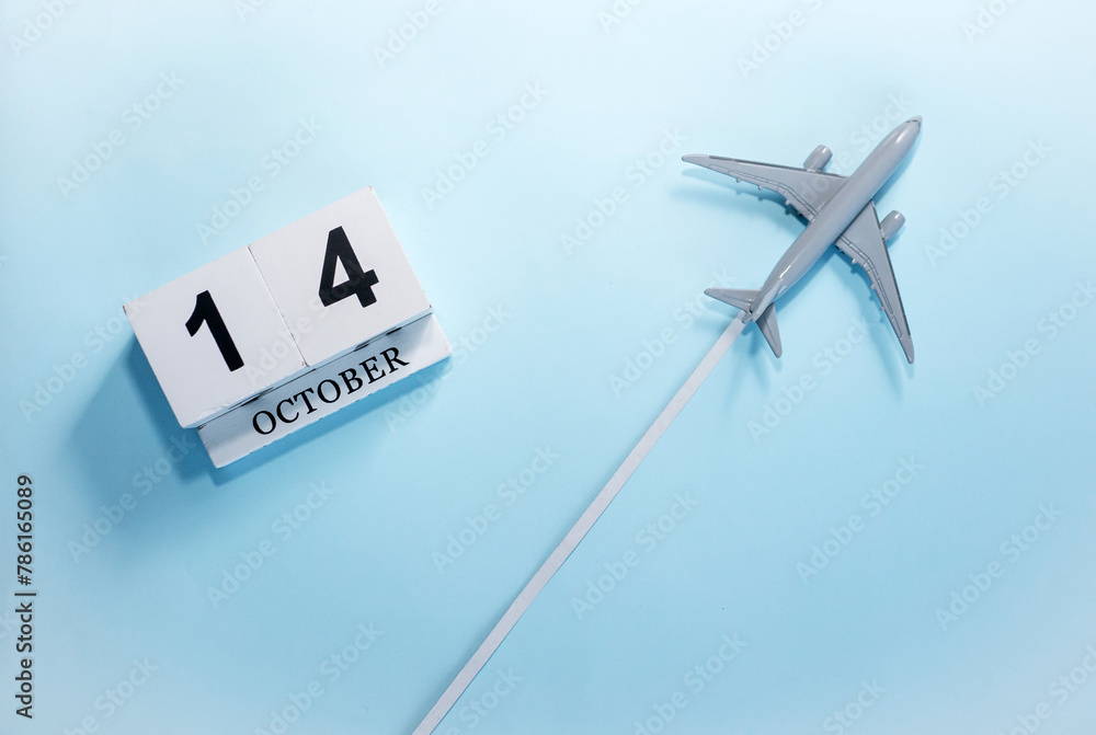 October calendar with number 14. Top view of a calendar with a flying passenger plane. Scheduler. Travel concept. Copy space. October calendar with number 14. Top view of a calendar with a flying passenger plane. Scheduler. Travel concept. Copy space.