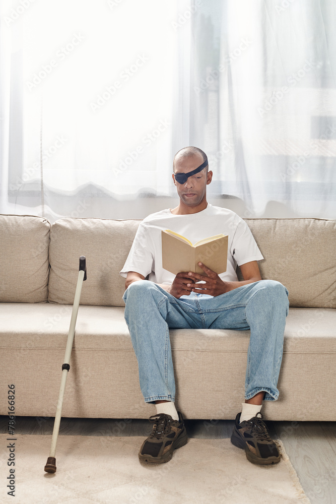 A man with Myasthenia Gravis, an African American, is engrossed in reading a book while sitting comfortably on a couch.