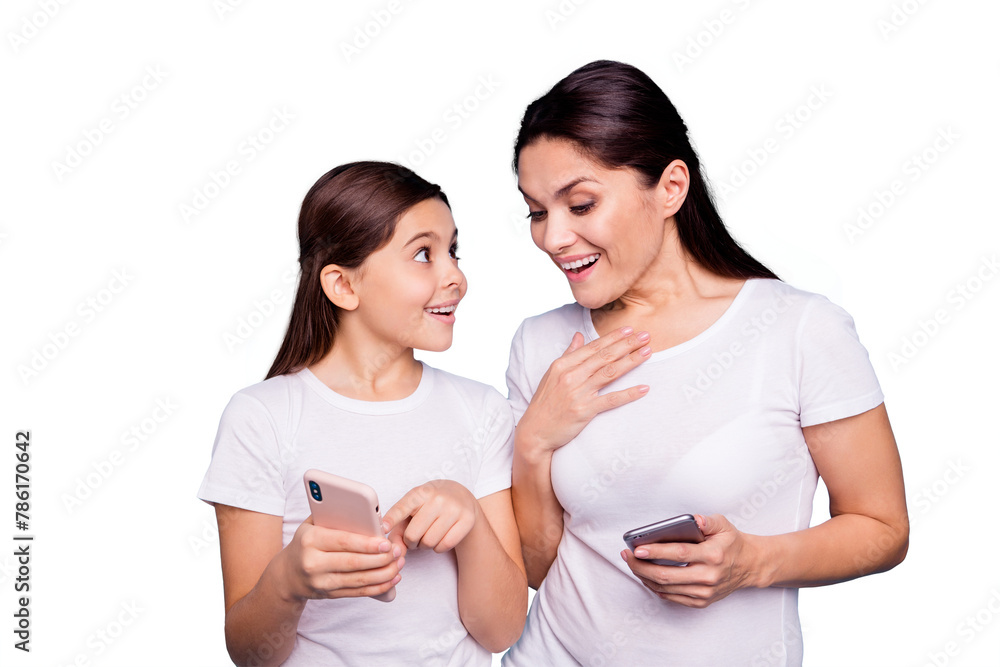 Fototapeta premium Close up photo beautiful two people brown haired mom small little daughter shows telephone look wondered great news can not believe own eyes wear white t-shirts isolated bright blue background