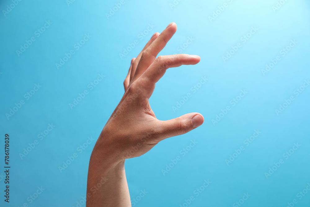 Man holding something in hand on light blue background, closeup Man holding something in hand on light blue background, closeup