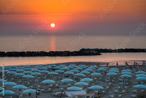 Beautiful sunrise on Rimini beach with umbrellas