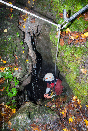 Quadro su tela A speleologist man exploring a huge hidden cave hanging on a rope for safety an