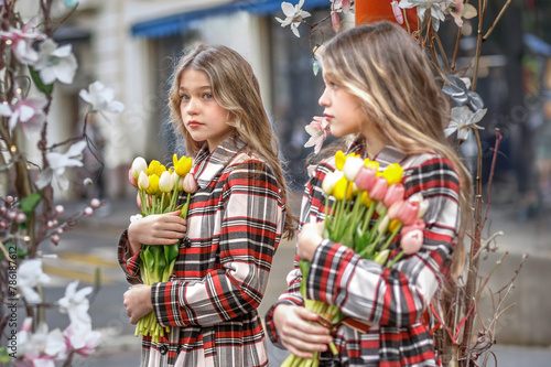 A teenage girl stands at a mirror on the street with tulips. Spring. City photo. Reflection