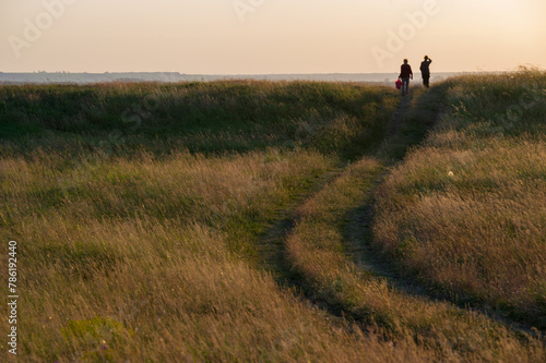 Two silhouettes of women walking around the field in the evening.