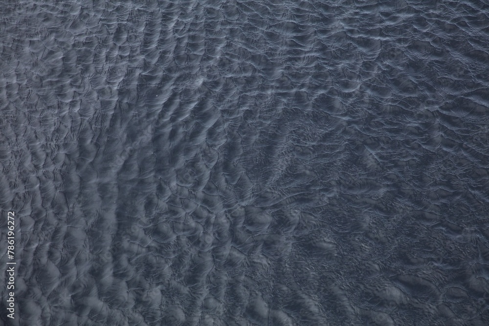 Abstract water surface with ripples and waves as background, top view.