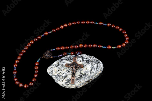 Crucifix and Rosary Beads on a Granite Rock on a Black Background