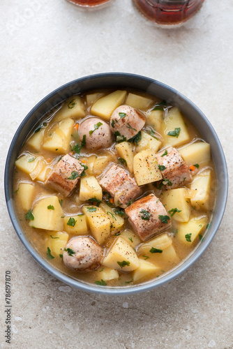 Photography Dublin coddle served in a grey plate, vertical shot on a beige stone background,