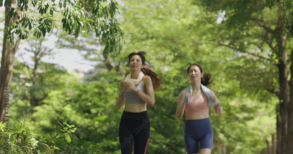 two Asian women engaging in physical activity within an urban park. They are incorporating smart devices to monitor and track their body data using technology. two Asian women engaging in physical activity within an urban park. They are incorporating smart devices to monitor and track their body data using technology.