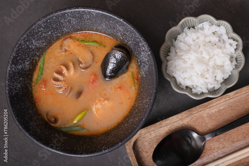 Tom yum soup with seafood and rice ondark background top view photo