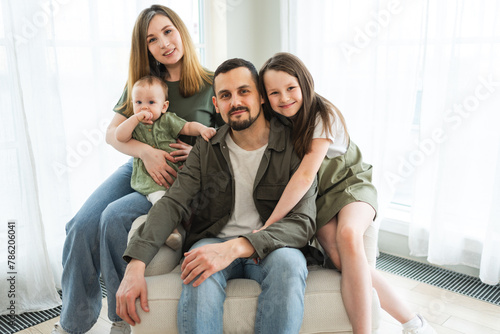 Happy family at home. Mother father two children daughters relaxing indoor. Mom dad parents baby girls kids relax playing having fun together. Family smiling laughing enjoying tender love moment