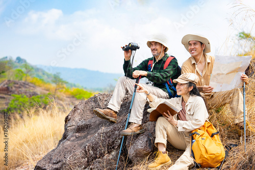 group of three hikers sitting together on the top of mountain,cheerful asian family happy while hiking on summer time