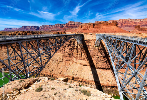 Twin spandrel arch bridges over Marble Canyon washed out by Colorado river called new and historic “Navajo Bridge“. Tall majestic steel constructions from 1929 and 1995 built next to each other.