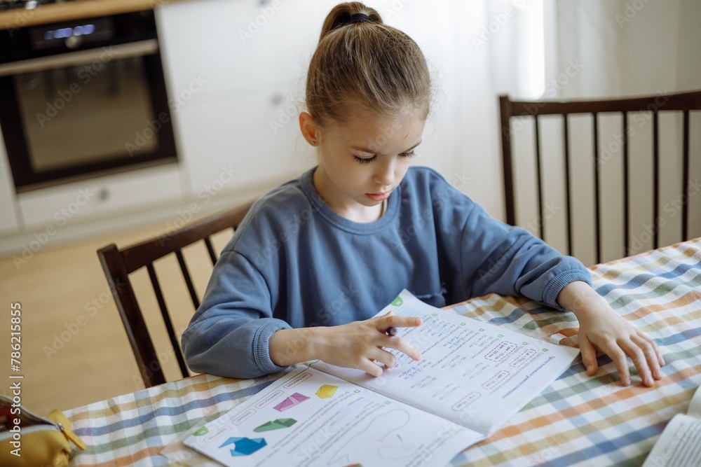 an independent 7-year-old girl doing her school homework at home in the kitchen an independent 7-year-old girl doing her school homework at home in the kitchen