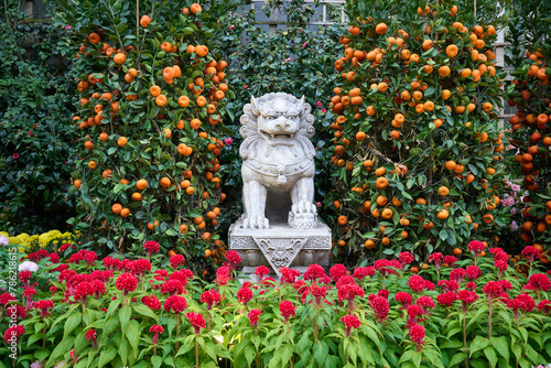 Lion statue between the orange trees and flowers
