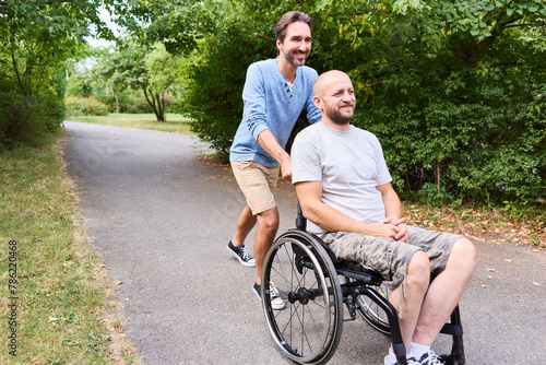 Smiling man using a wheelchair enjoying a day at the park with a friend