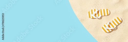 Summer vacation concept. Aerial view of pair flip flops on the sandy coastline. Tropical background for postcard, flyer, poster, banner. 3D illustration with copy space, rendering.