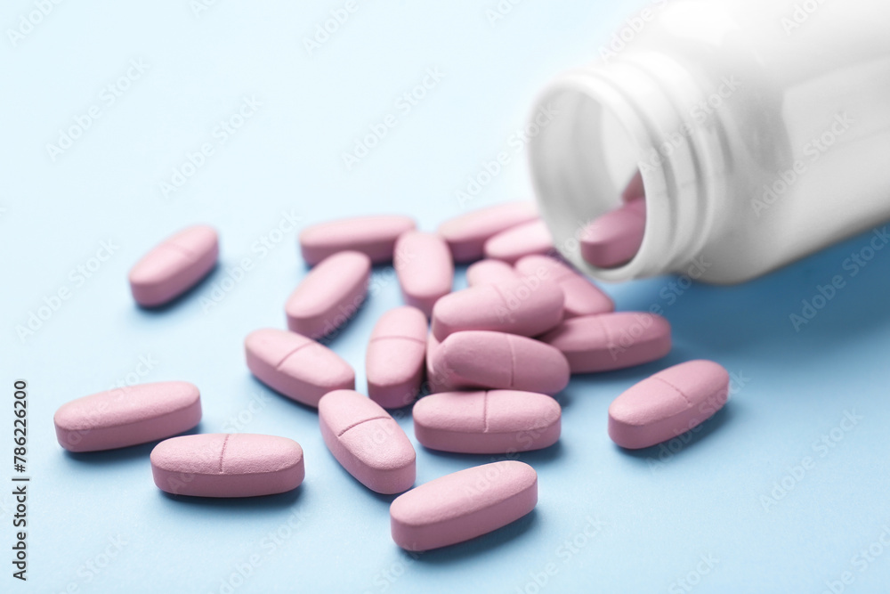 Vitamin pills and bottle on light blue background, closeup Vitamin pills and bottle on light blue background, closeup