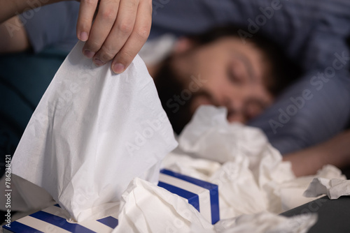 Man hand taking pulling white facial tissue out of from white box clean handkerchief, selective focus. Concept: healthcare medicine, allergy awareness week (May 14-20), nasal diseases, allergy day  photo