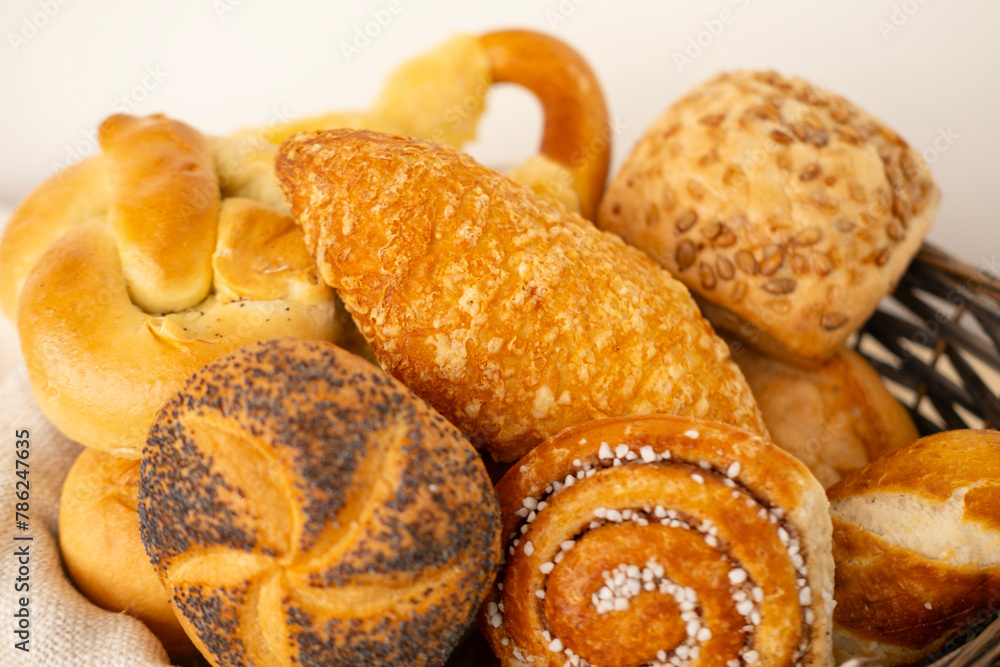 wicker basket overflowing with freshly baked pastries: cheese and poppy seed buns, pretzels, and sweet curd tarts