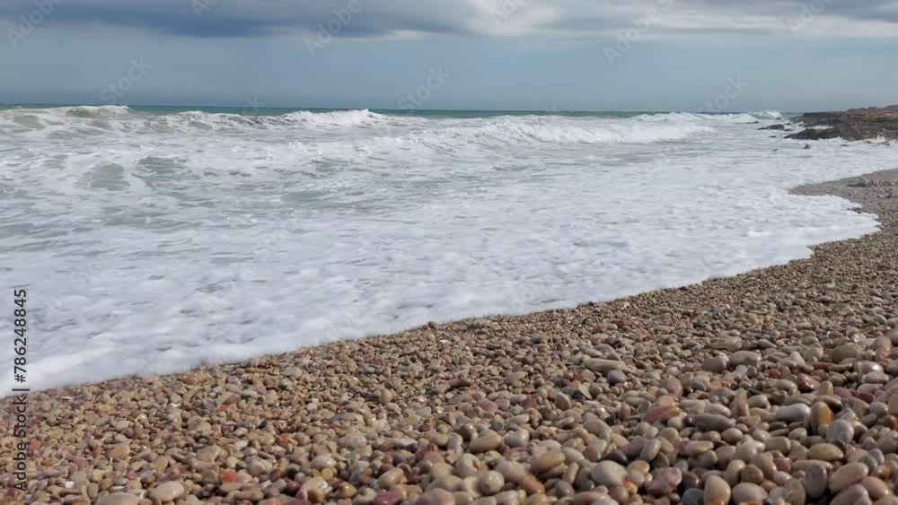 Continuous ocean waves drench a sandy and rocky beach, suitable for use as a dynamic vacation background in creative projects. Continuous ocean waves drench a sandy and rocky beach, suitable for use as a dynamic vacation background in creative projects.