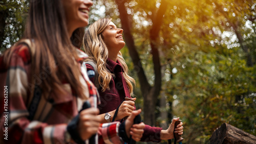 Front view with lens flare of mixed race and Caucasian female friends in 20s and 30s smiling as they enjoy late afternoon day hike. Portrait of Female Friends Hiking