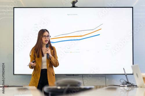 Presentation - Asian business woman people giving presentation and Report pointing at projector or TV screen. People Work in Business Office.