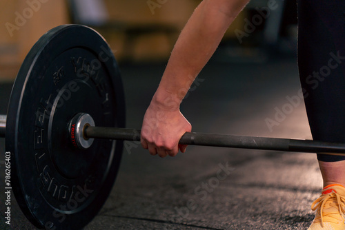 close-up in a sports club a trainer's hand is about to lift a barbell with athletic plates