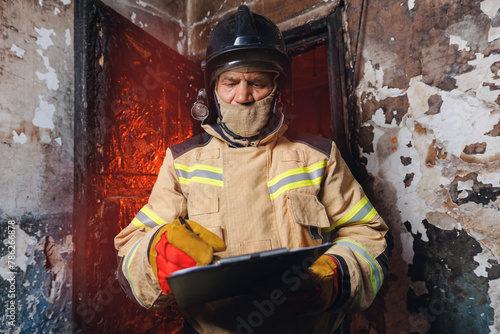 Fireman inspector conducts investigation to determine circumstances of fire in house and uses clipboard for report incident. Concept Insurance payments and checklist © Parilov