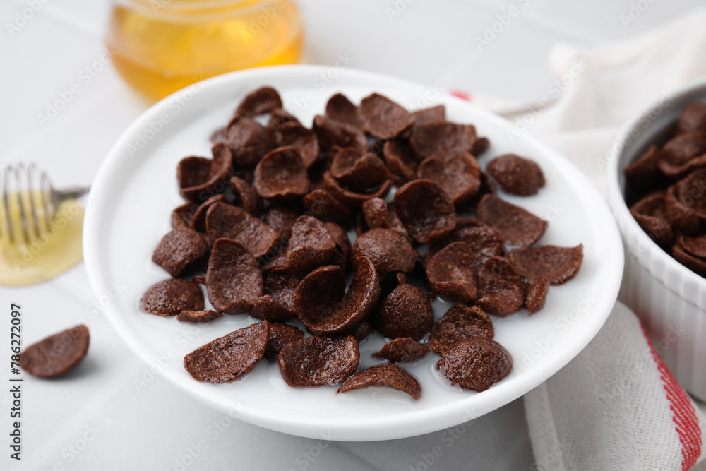 Breakfast cereal. Chocolate corn flakes and milk in bowl on white table, closeup Breakfast cereal. Chocolate corn flakes and milk in bowl on white table, closeup