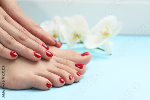 Woman with stylish red toenails after pedicure procedure on light blue background  closeup. Space for text