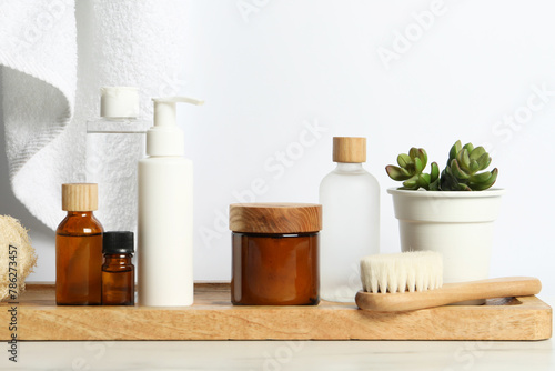 Different bath accessories and personal care products on light table near white wall