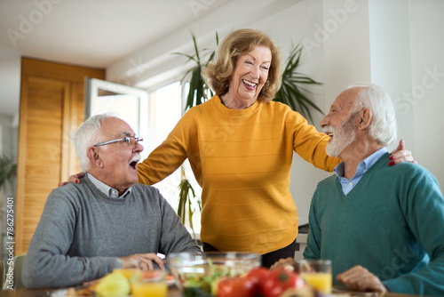 Group of happy mature friends talking while having a meal at dining table.	