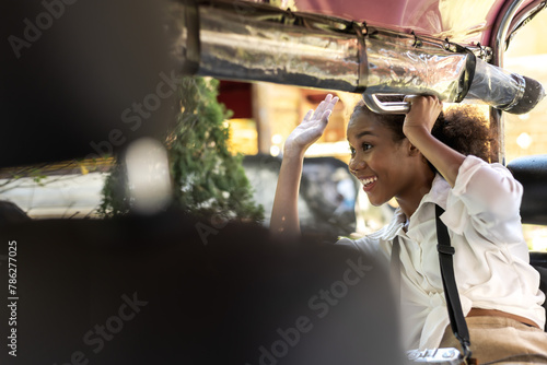 Happy black tourist woman sitting in local tuktuk exploring Thailand during summer vacation