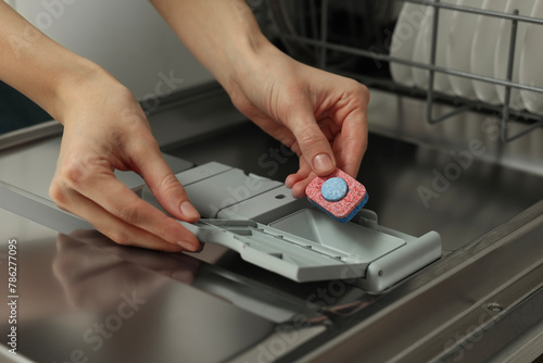 Woman putting detergent tablet into open dishwasher, closeup © New Africa