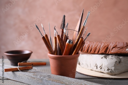Clay and set of crafting tools on grey wooden table in workshop, closeup