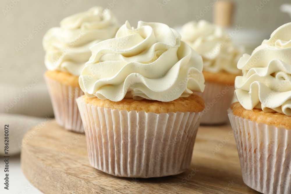 Tasty vanilla cupcakes with cream on table, closeup Tasty vanilla cupcakes with cream on table, closeup