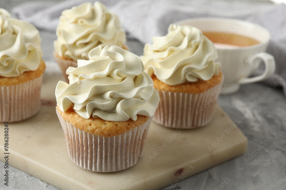 Tasty cupcakes with vanilla cream on grey table, closeup Tasty cupcakes with vanilla cream on grey table, closeup