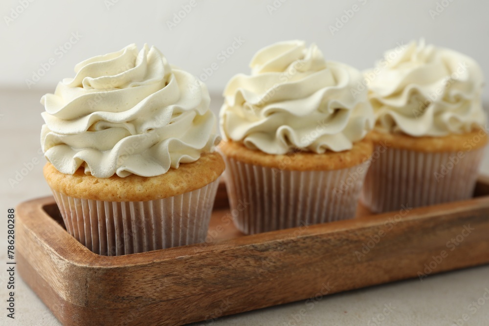 Tasty cupcakes with vanilla cream on light grey table, closeup Tasty cupcakes with vanilla cream on light grey table, closeup