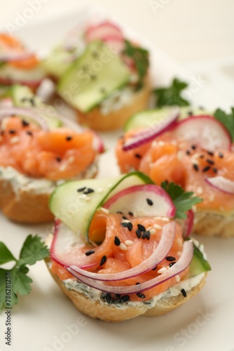 Tasty canapes with salmon served on table, closeup