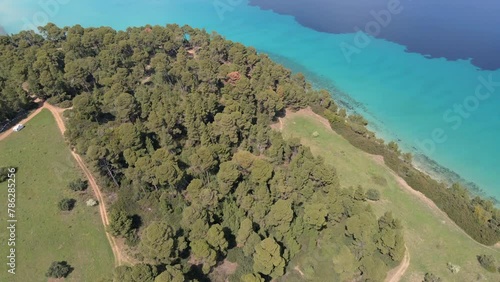 Top down aerial view of wild beach with crystal clear water  with trees in Kallithea Halkidiki, Greece