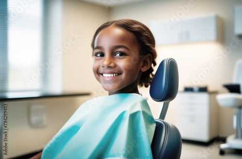 Black girl in dentist chair, looks happy with treatment, against the blurry background of a doctor's office. Children's dentistry, routine checkup, no fear of treatment and pain