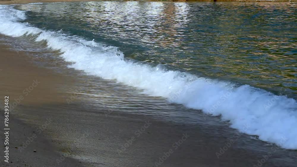 Detail of Tamariu beach with the waves breaking gently on the sand. Costa Brava, Catalonia, Spain Detail of Tamariu beach with the waves breaking gently on the sand. Costa Brava, Catalonia, Spain