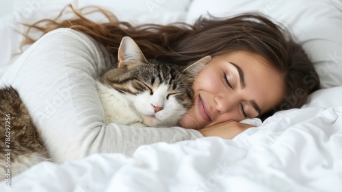 Peaceful scene of a young woman and a cat sleeping together on a white bed at home
