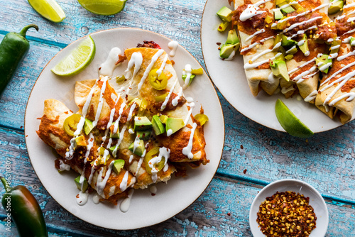 Top down view of taquitos topped with salsa, avocado and sour cream drizzle. photo