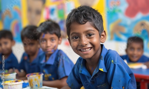 Cheerful Indian primary school boys wearing blue shirts smiling at camera in painting class classroom at school photo